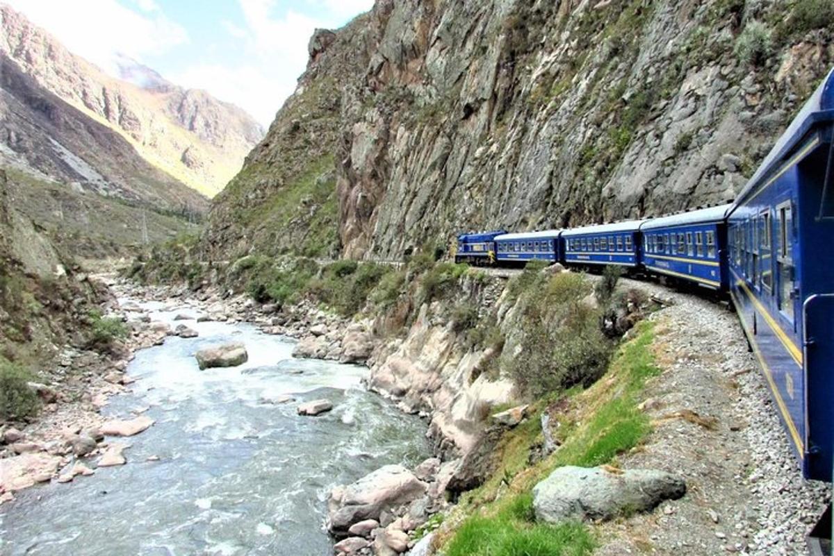 un treno blu che viaggia attraverso un fiume di montagna