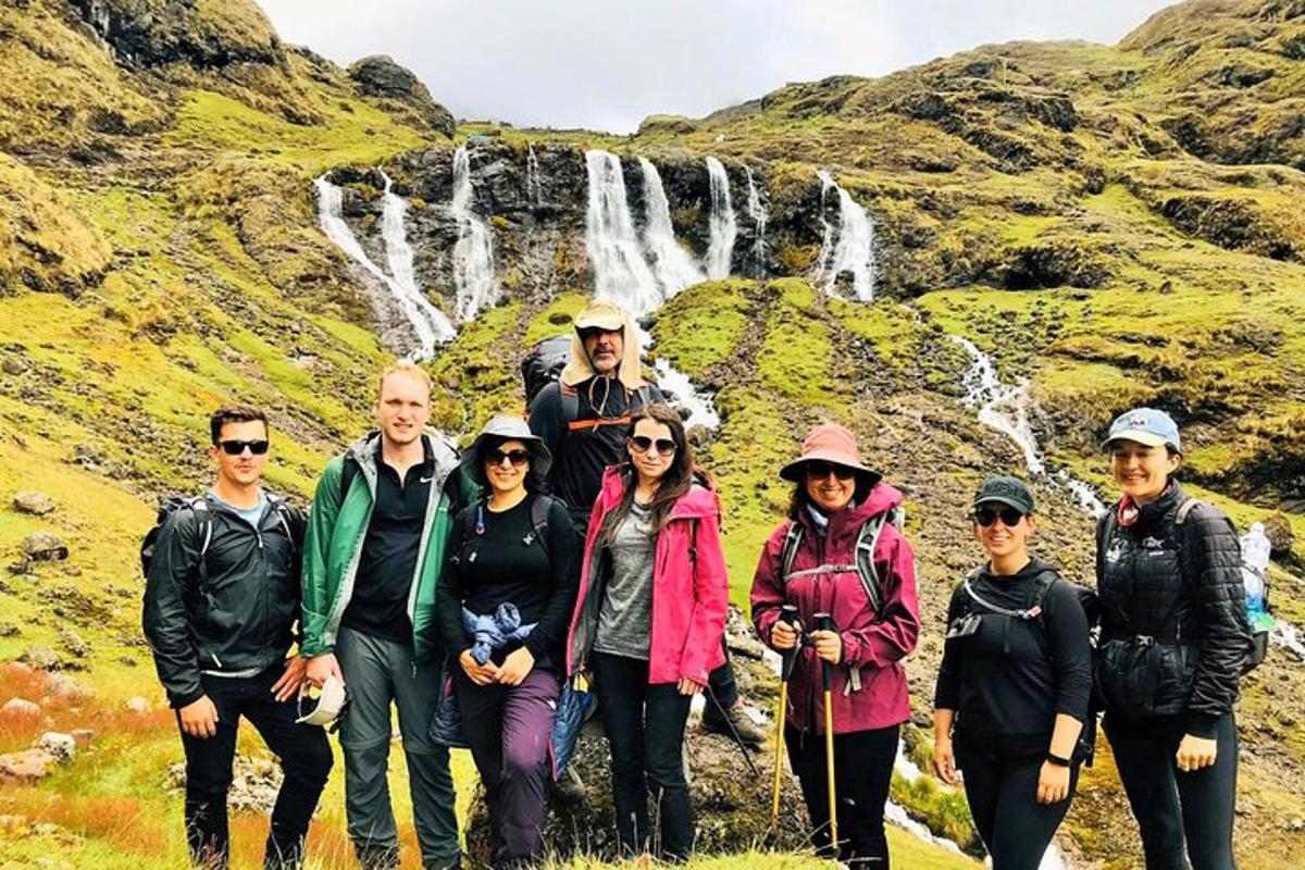 um grupo de pessoas em pé em frente a uma cachoeira