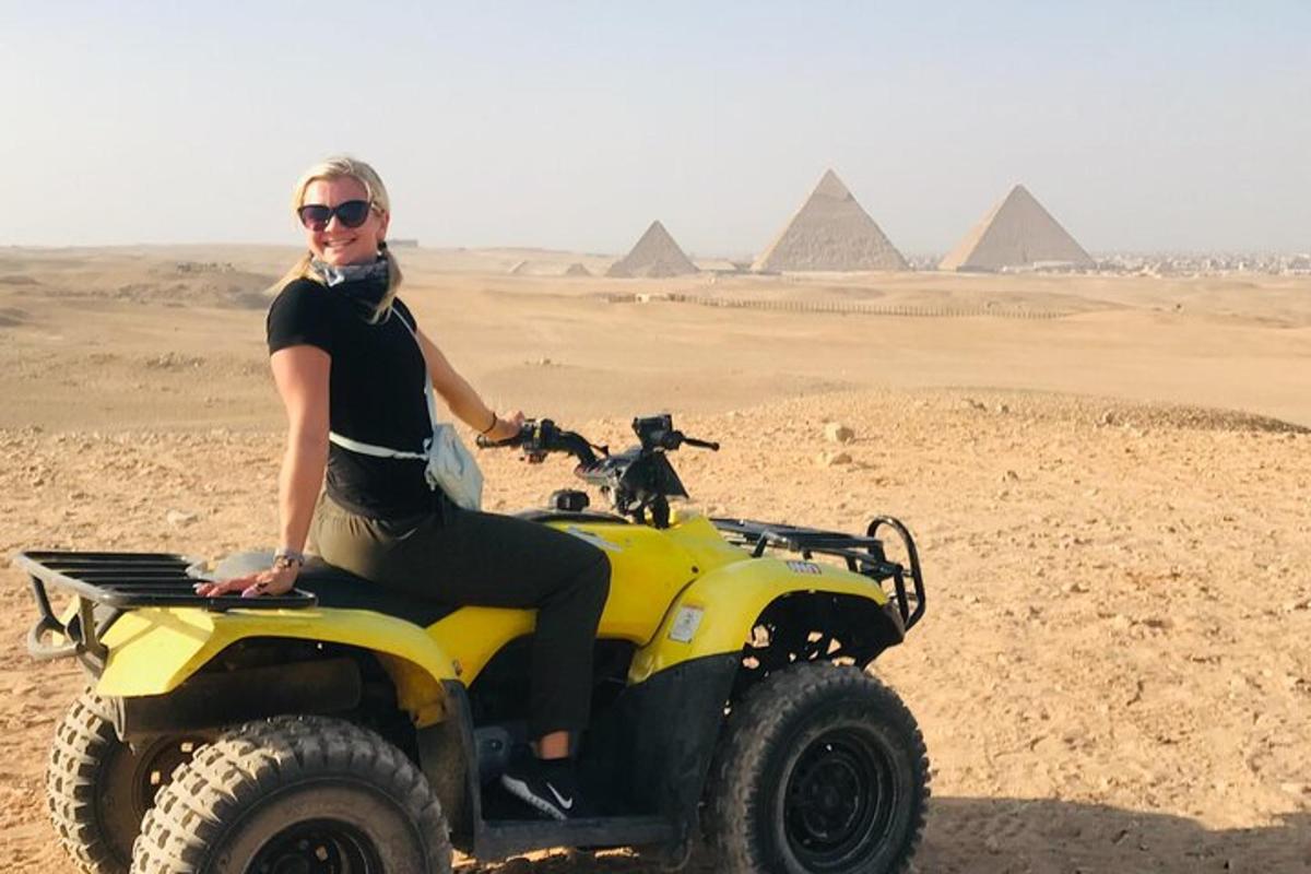 a woman sitting on a atv in front of pyramids