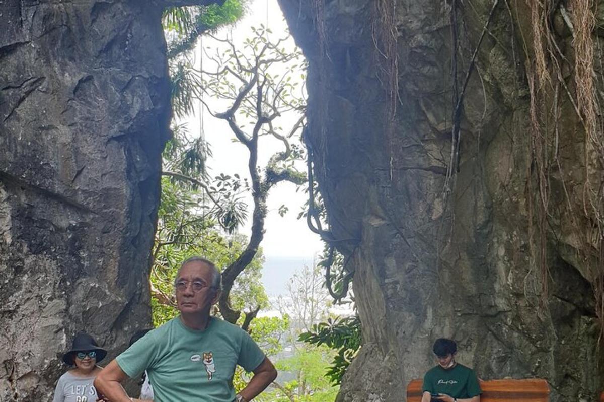 a man standing next to a bench in a rock wall