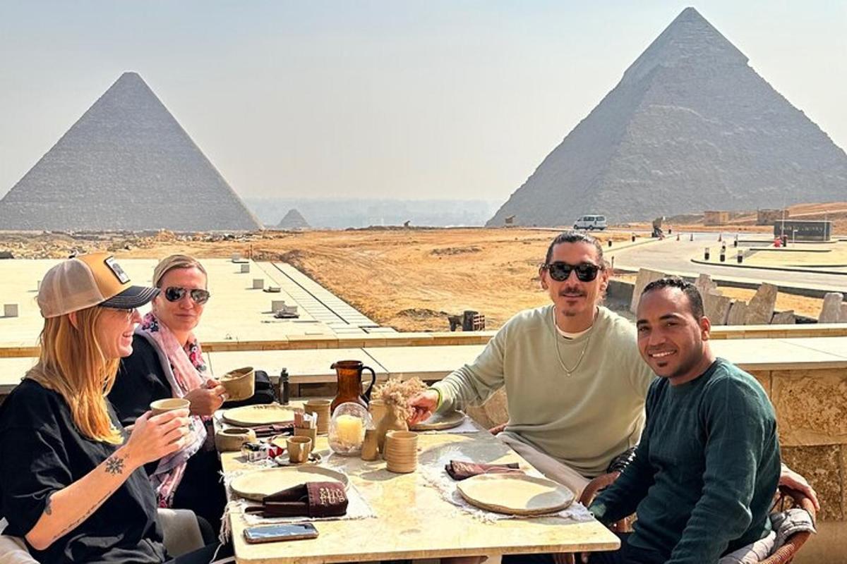 eine Gruppe von Menschen sitzt an einem Tisch vor den Pyramiden