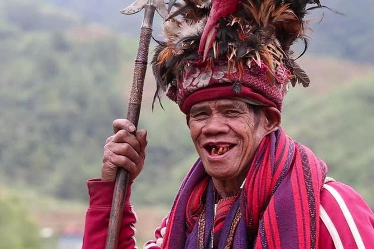 an old man wearing a headdress holding a stick