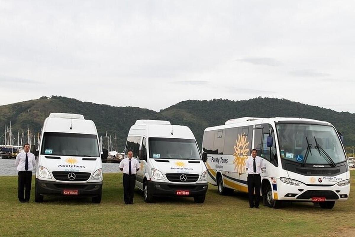 Skupina tří bílých autobusů zaparkovaných na poli