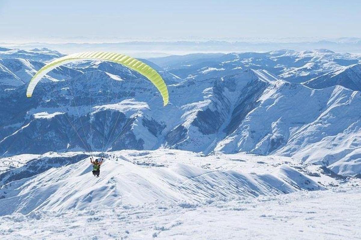 maður sem flýgur fallhlíf upp á fjallstindi