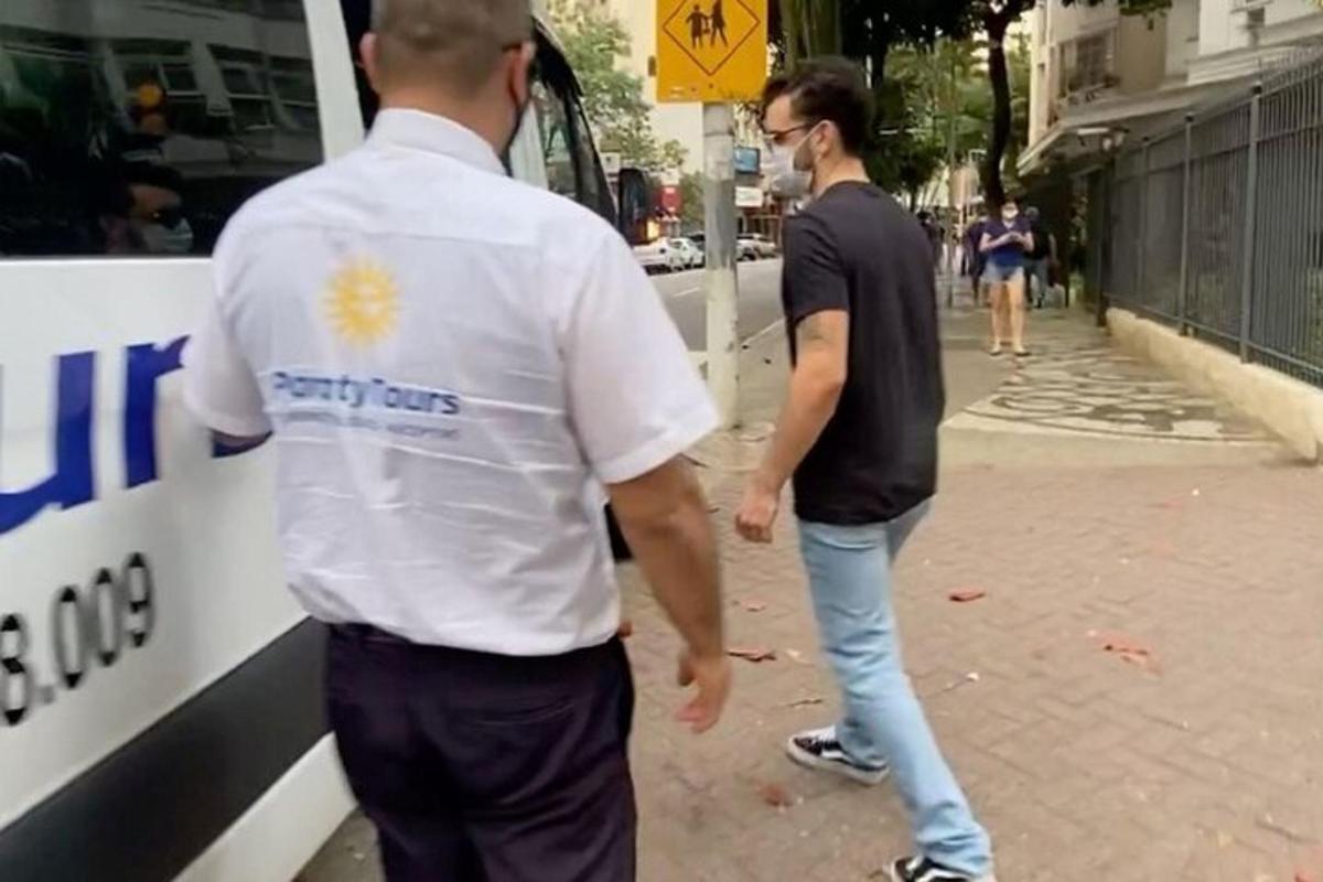 Δύο άντρες περπατούν σε έναν δρόμο δίπλα σε ένα λεωφορείο