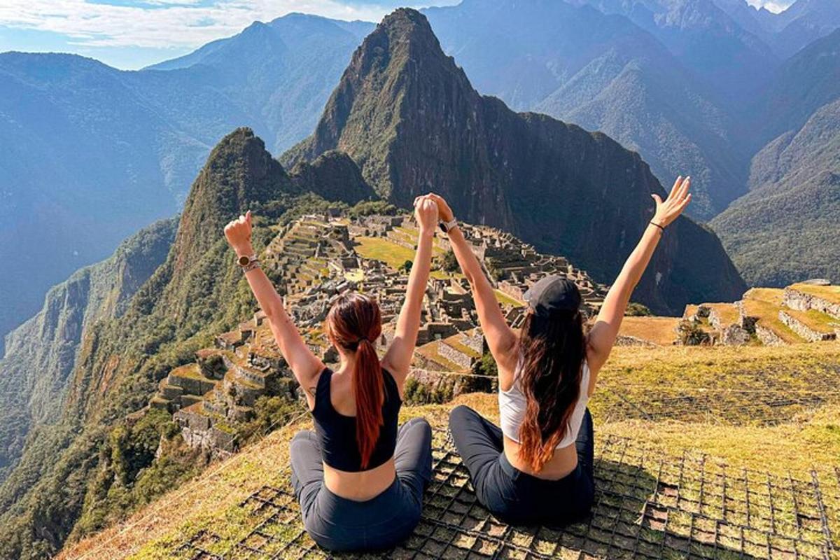 zwei Mädchen sitzen auf einem Berggipfel mit ihren Händen in der Luft