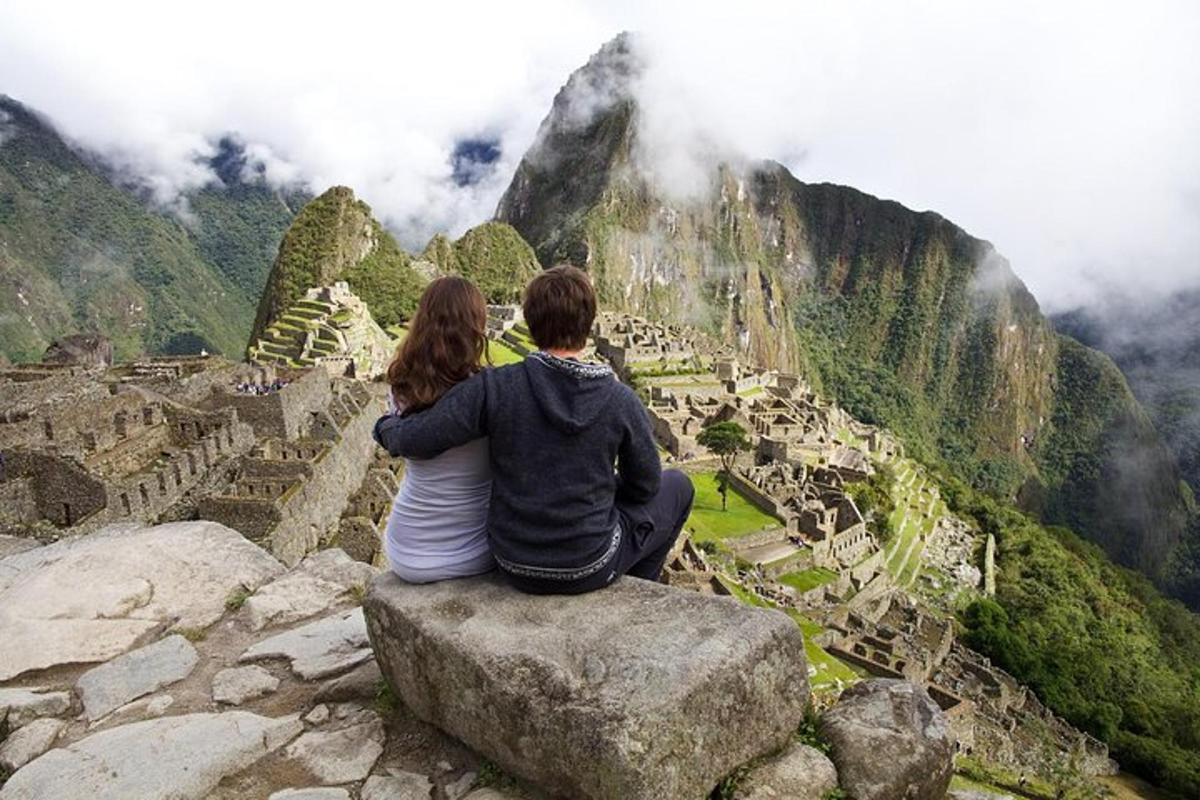 Egy pár ül egy sziklán, és a Machu Picchu-t nézi