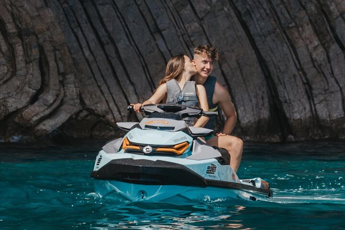 un home i una dona muntant una moto aquàtica a l'aigua