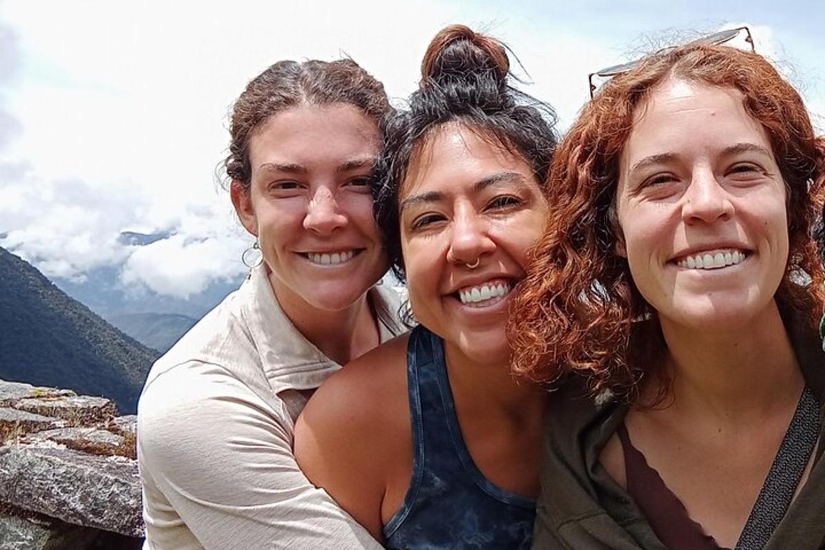 Tres mujeres posando para una foto en la cima de una montaña