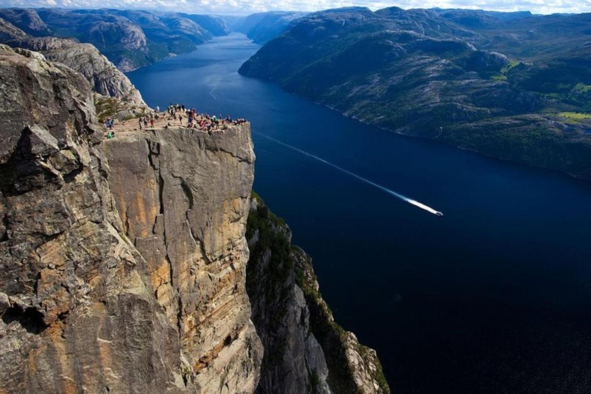 en gruppe mennesker på kanten av en klippe med utsikt over en innsjø