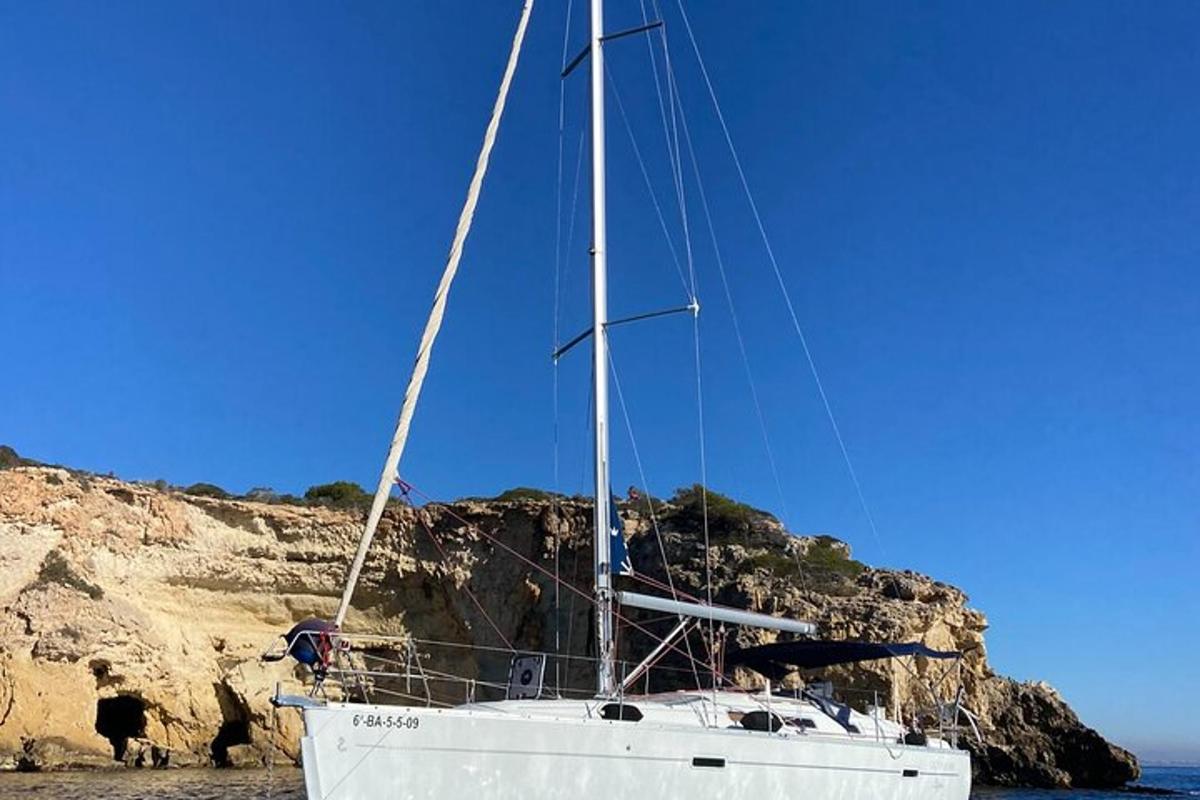 una barca a vela seduta nell'acqua accanto a una scogliera