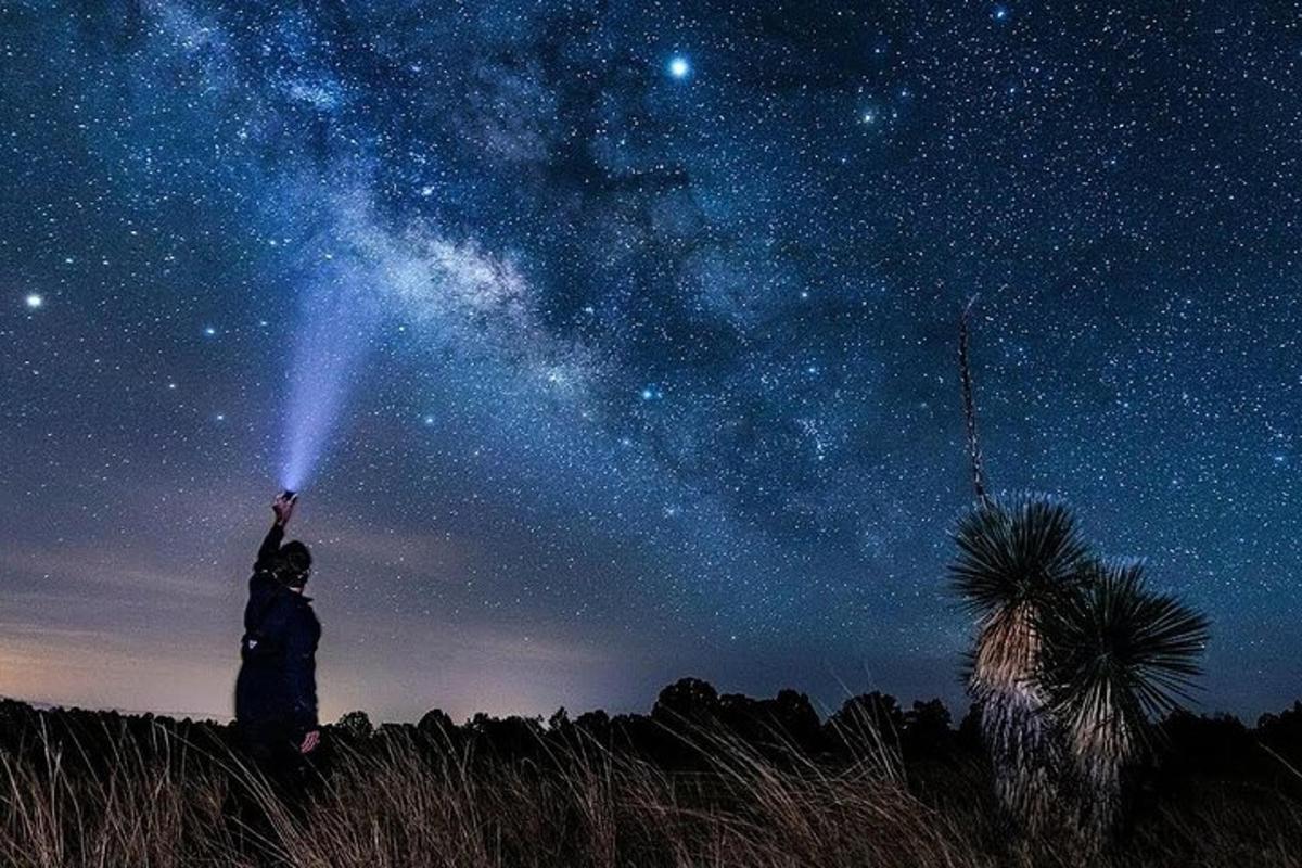 a person holding up a light in the night sky