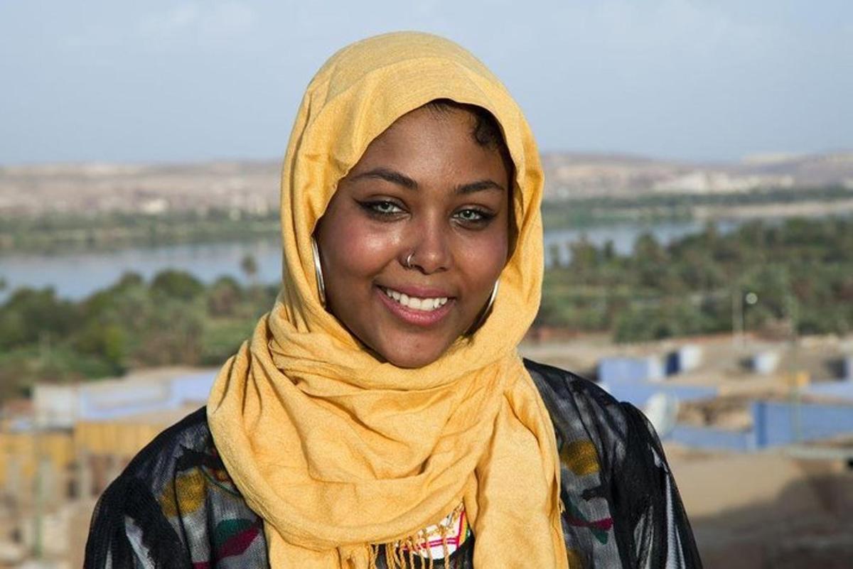 una donna che indossa un hijab giallo sorride alla telecamera