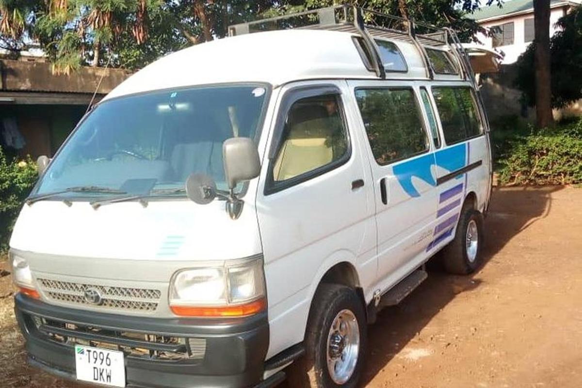 uma van branca estacionada em uma estrada de terra