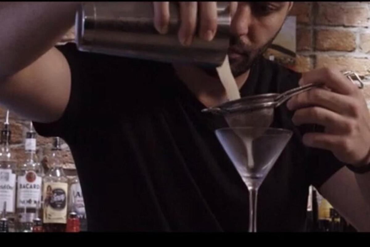 a man is making a drink in a martini glass