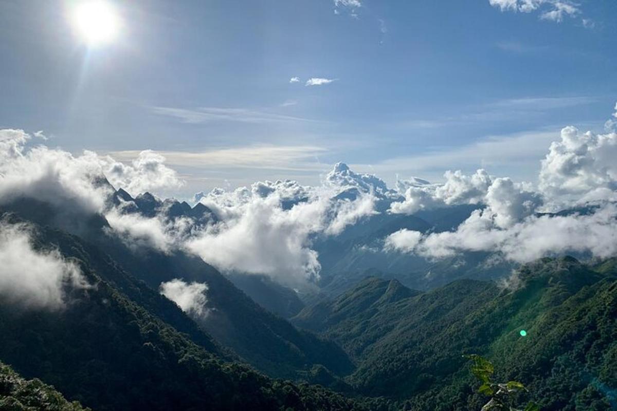 a view of a mountain range with the sun and clouds