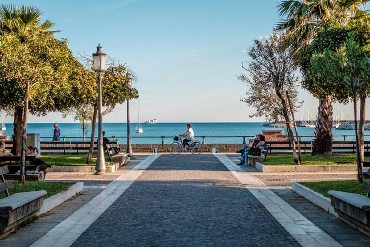 gente sentada en bancos en un parque cerca de la playa