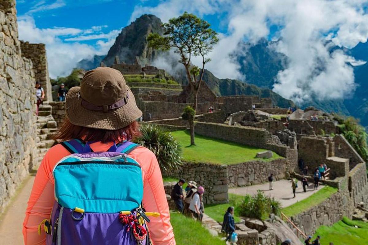 isang babaeng may backpack na nakatingin sa mga guho ng machu picchu