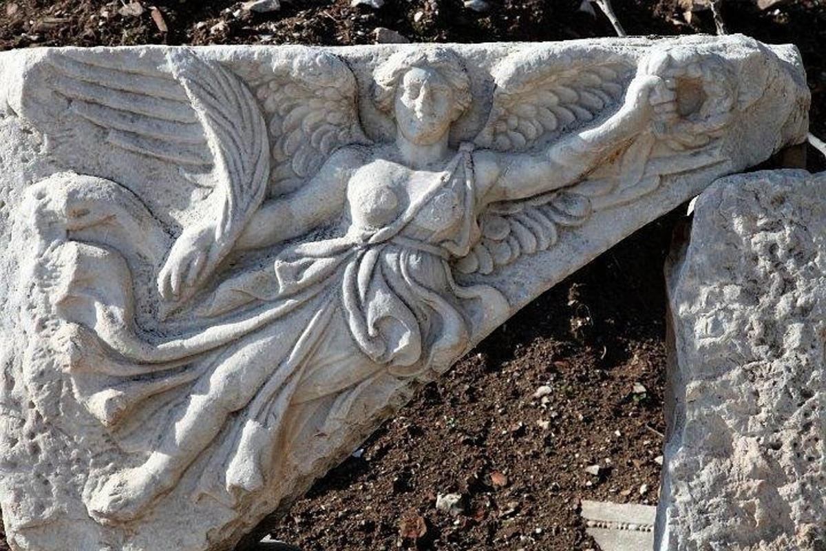 una estatua de piedra de un ángel sentado en el suelo