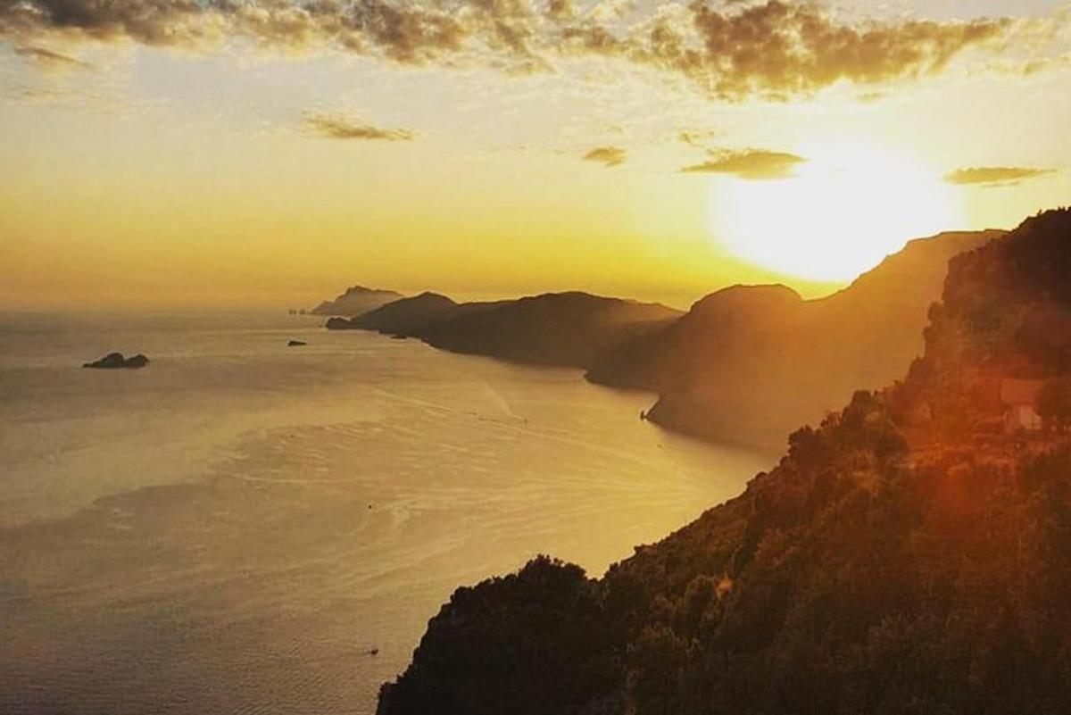 un apus de soare peste ocean cu un munte