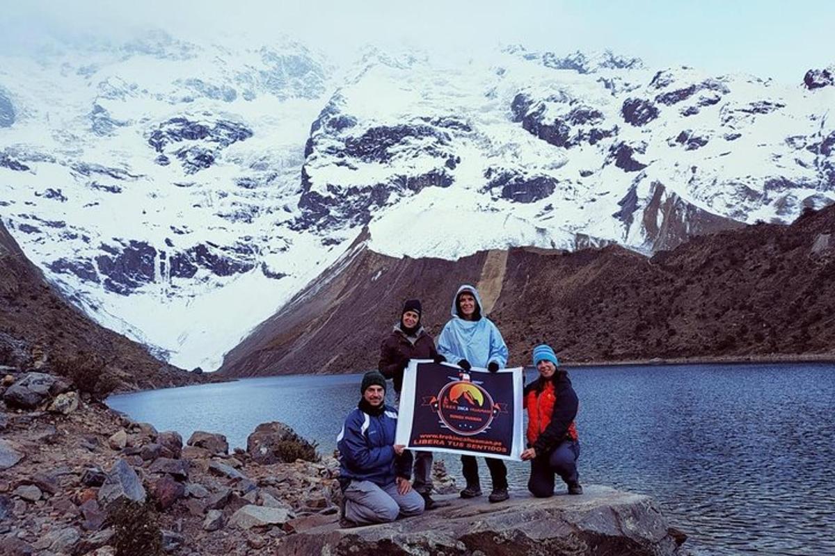 um grupo de pessoas segurando uma placa em frente a uma montanha