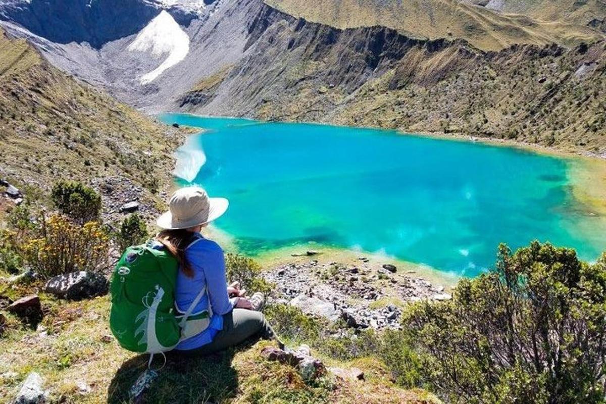 ženska sedi na gori in gleda na modro jezero