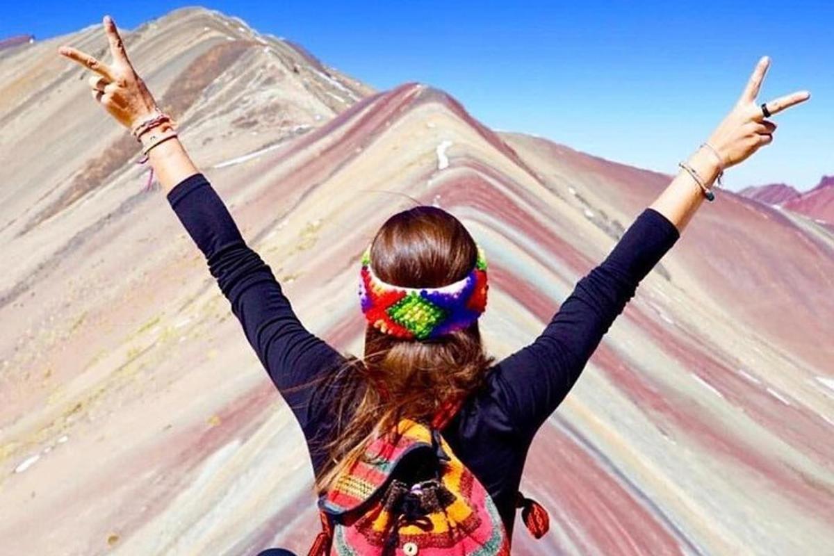 a woman with her arms up in front of a mountain