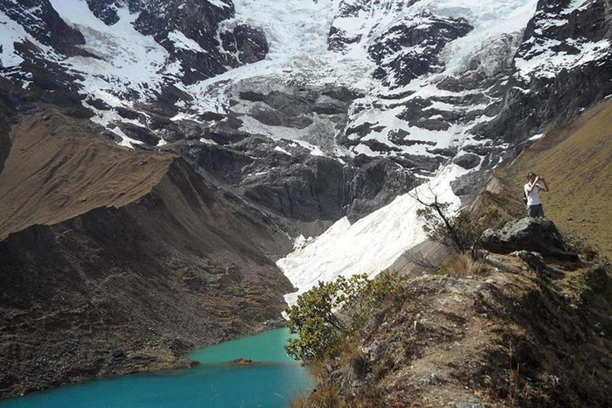 una persona in piedi sulla cima di una montagna che domina un lago