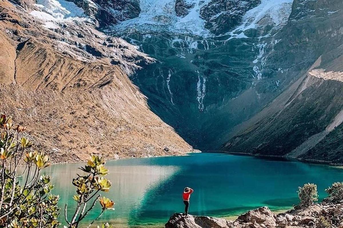 una persona in piedi su una roccia vicino a un lago di montagna