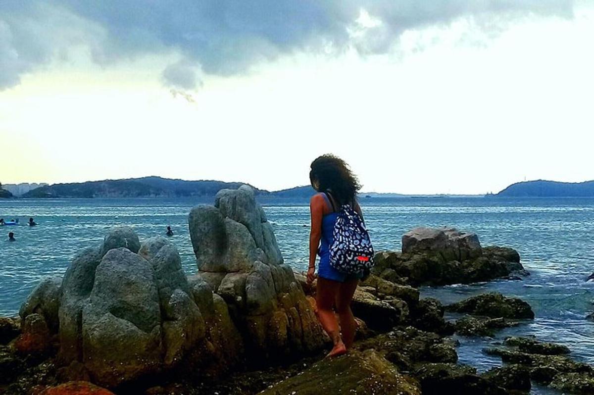 una donna in piedi su alcune rocce vicino all'acqua