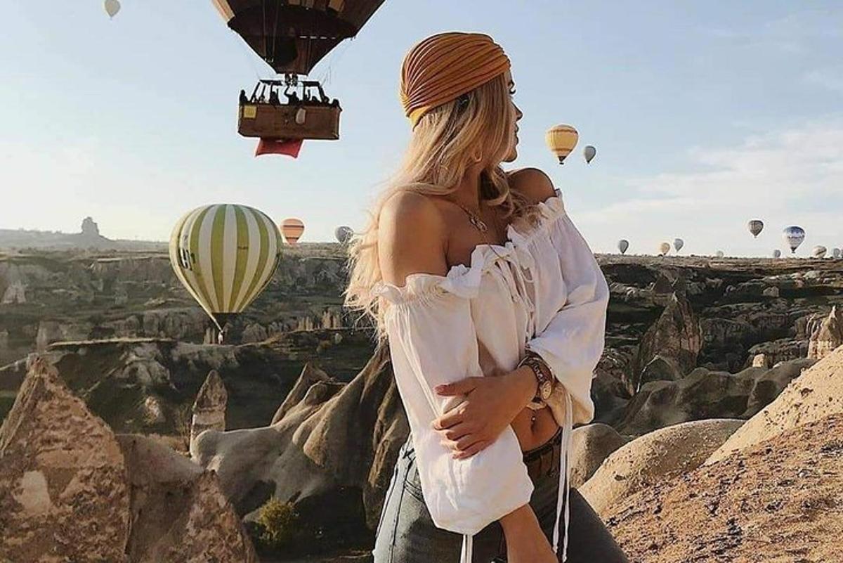 một người phụ nữ đứng trên vách đá với những khinh khí cầu
