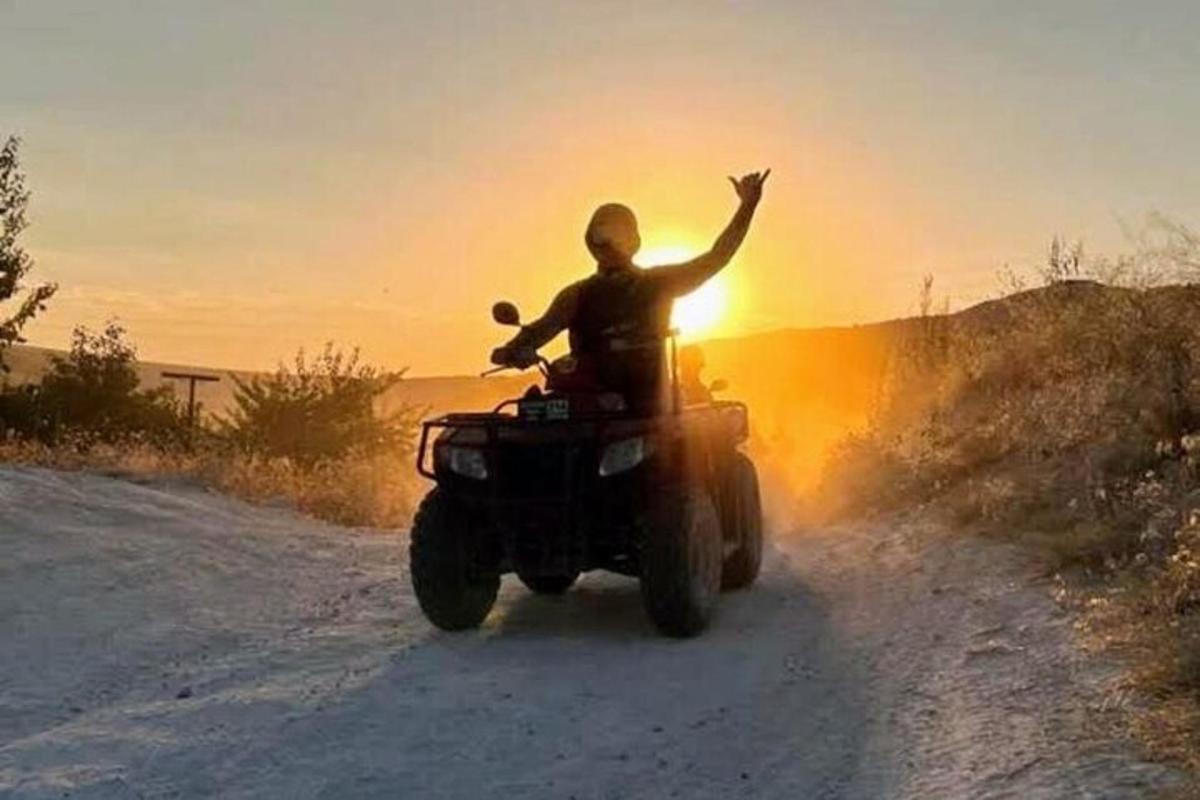 een man die op een quad over een onverharde weg rijdt
