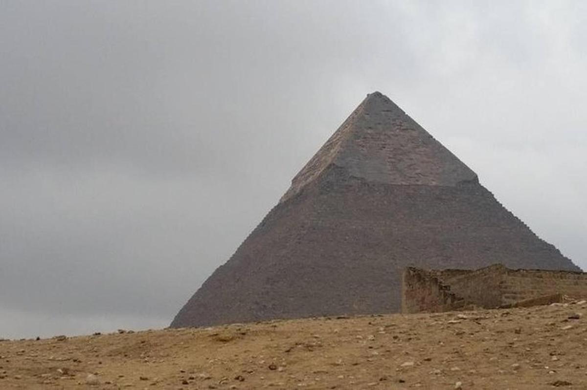 una pirámide en el desierto con un cielo nublado