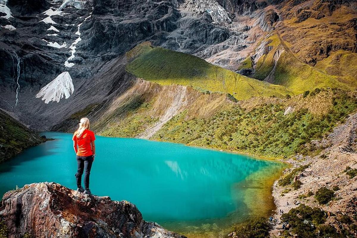 seorang wanita berdiri di atas gunung yang menghadap ke danau