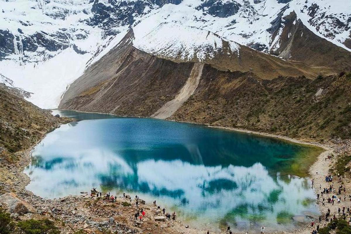 um grupo de pessoas em pé ao redor de um lago na montanha