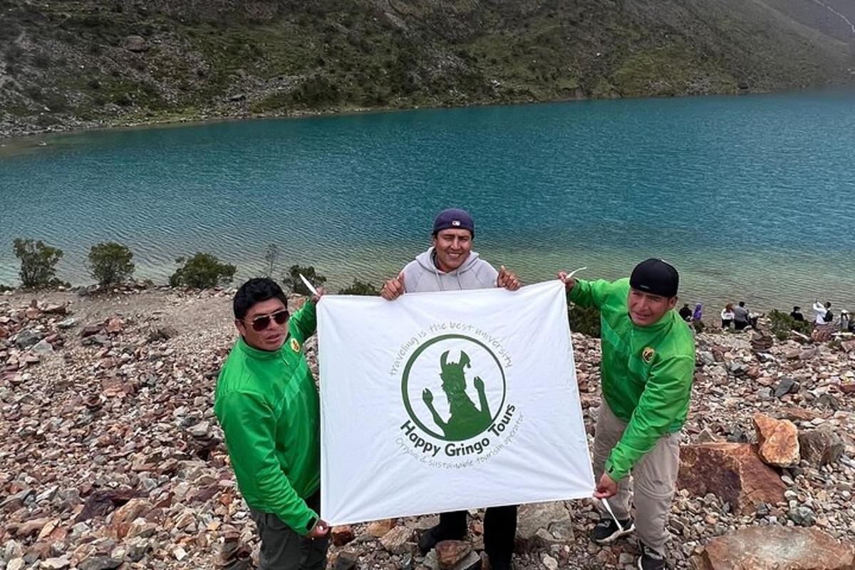 um grupo de três homens segurando uma bandeira em frente a um lago