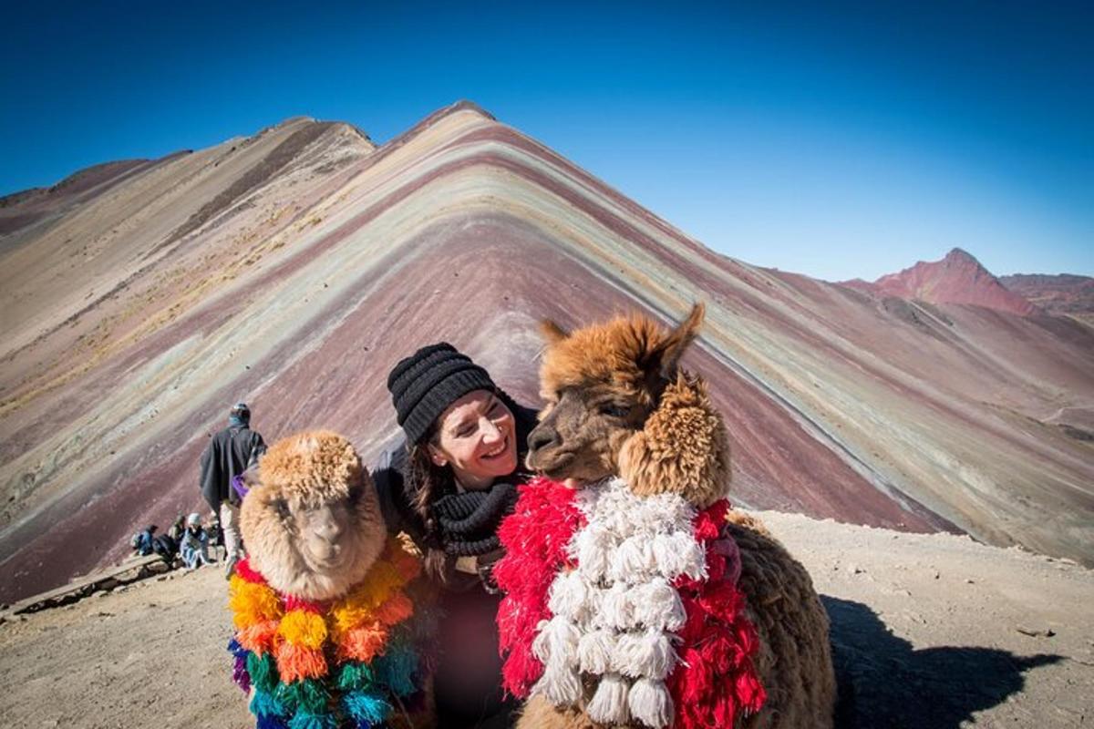 Una mujer posando con dos animales de peluche frente a una montaña.