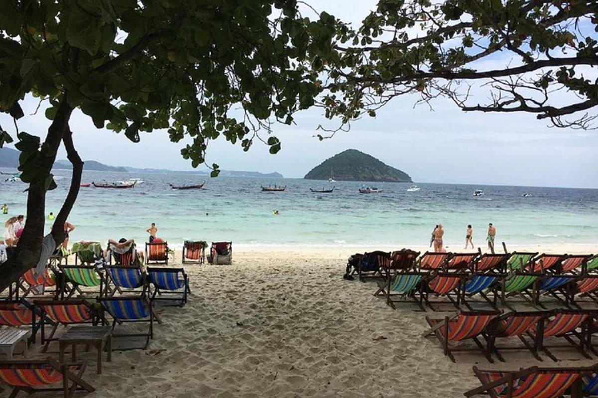 persone sedute su sedie su una spiaggia con vista sull'oceano