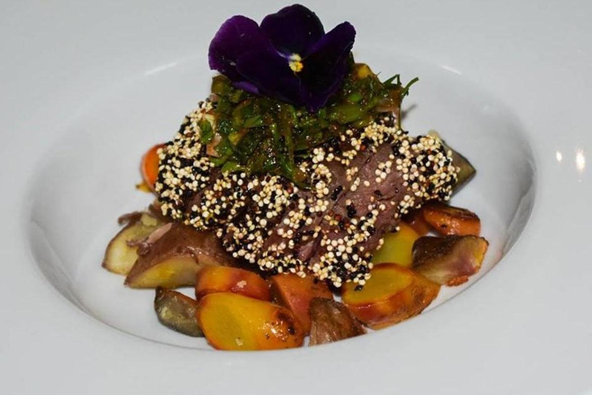Un plato de comida con una flor morada encima.