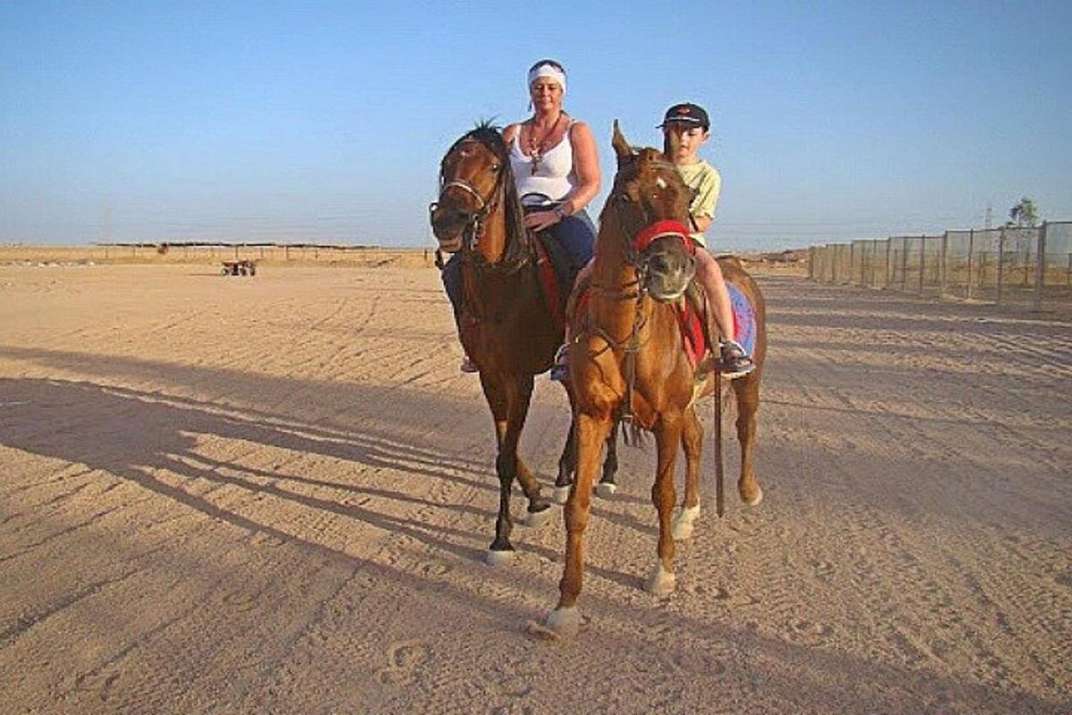 un homme et une femme à cheval dans le désert