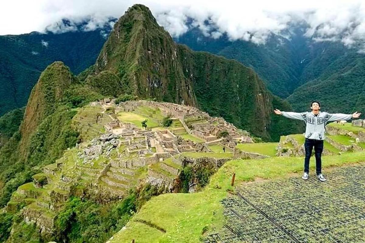 um homem em pé no topo de uma montanha com os braços estendidos