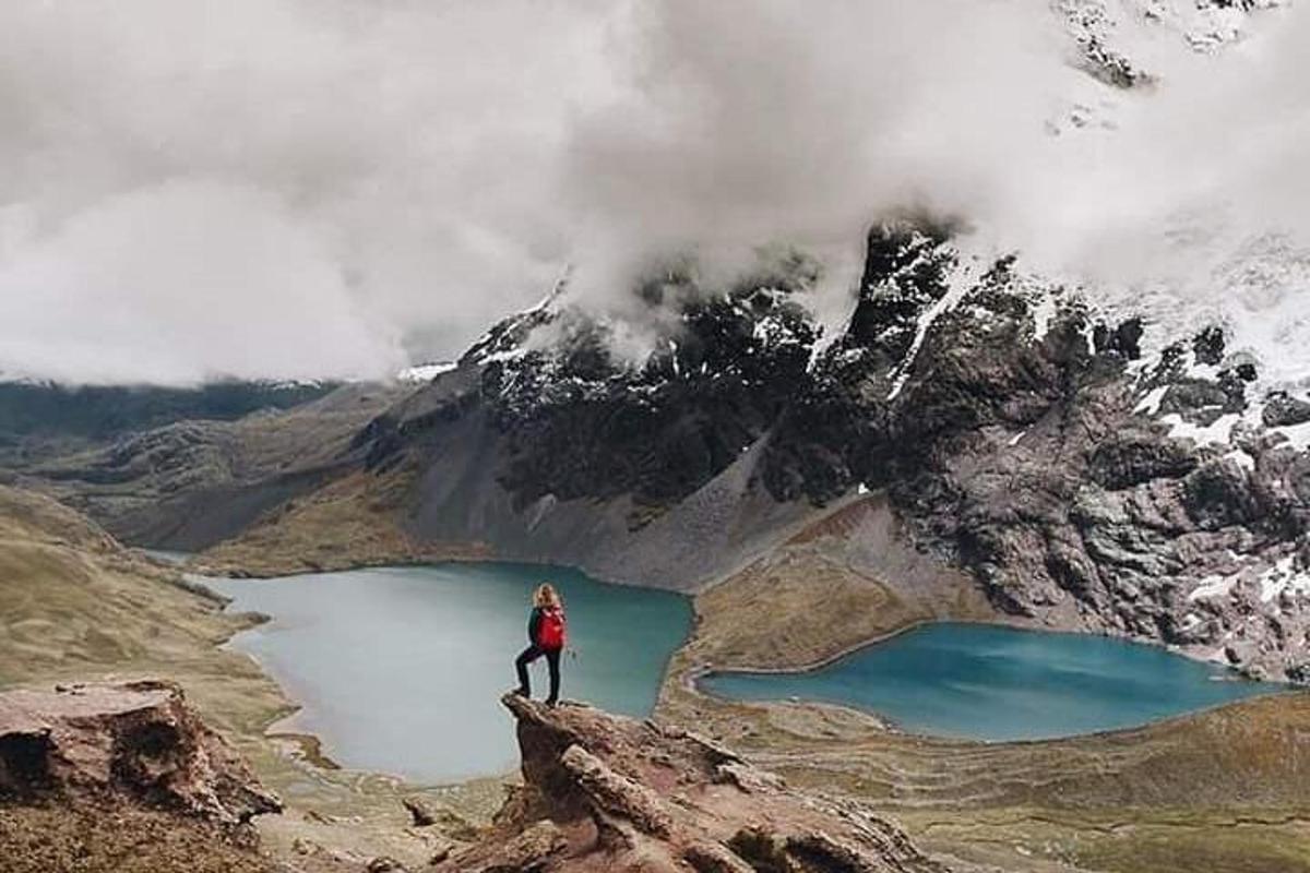 una persona in piedi su una roccia di fronte a un lago