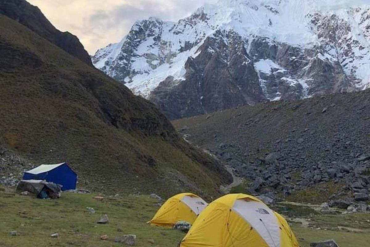 two tents in a field with mountains in the background
