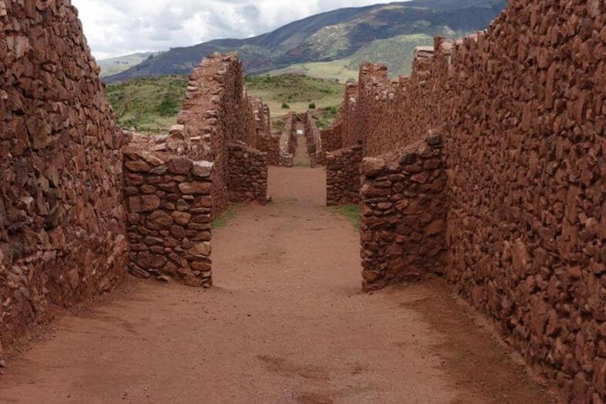 Un callejón en un edificio de piedra con montañas al fondo.