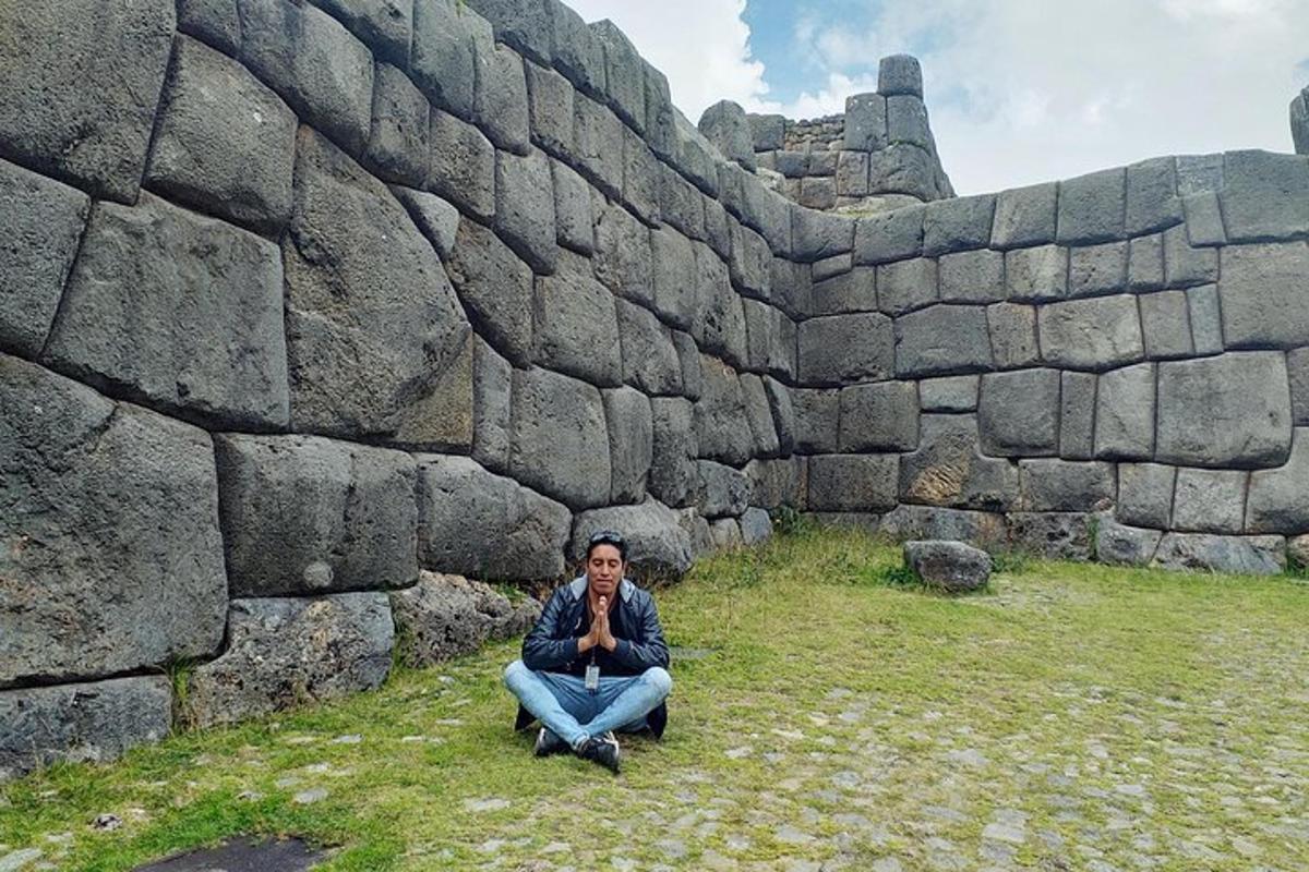 un home assegut davant d'un mur de pedra