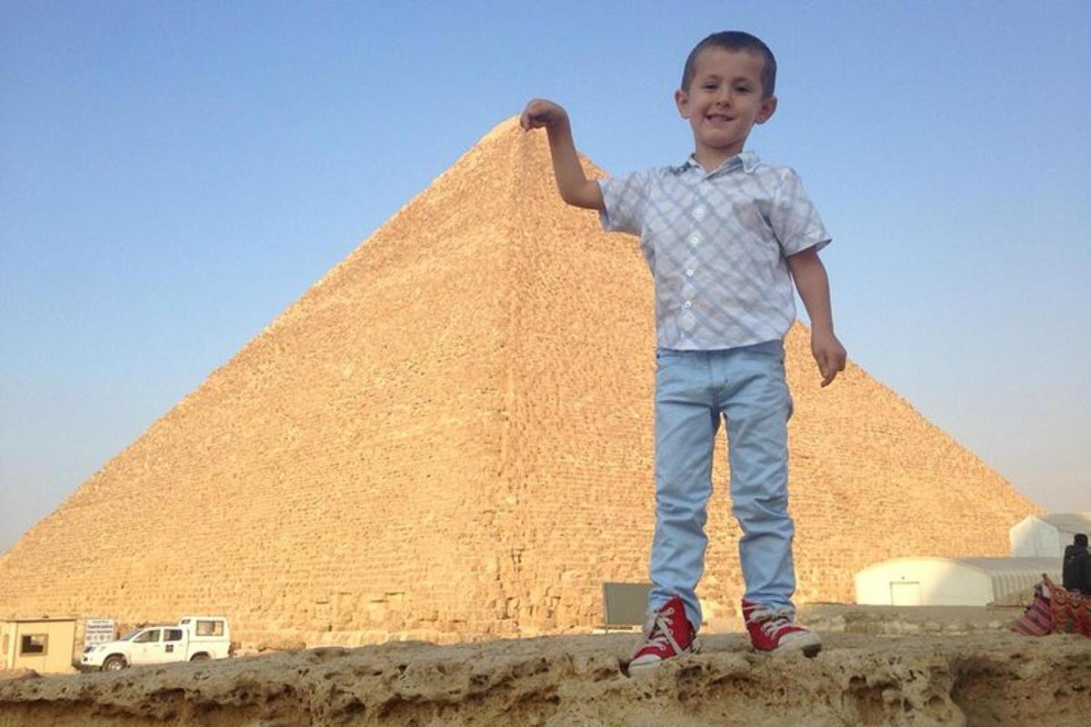 en ung gutt som står foran en pyramide