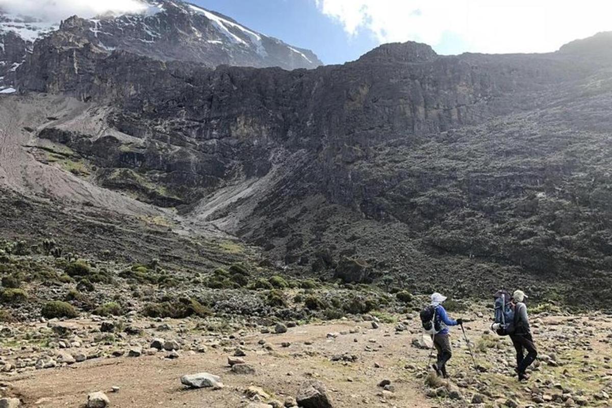Dos personas de pie en una montaña mirando un valle.