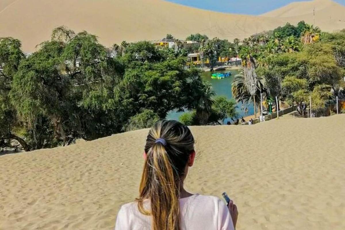 una donna in piedi su una duna di sabbia che guarda un fiume