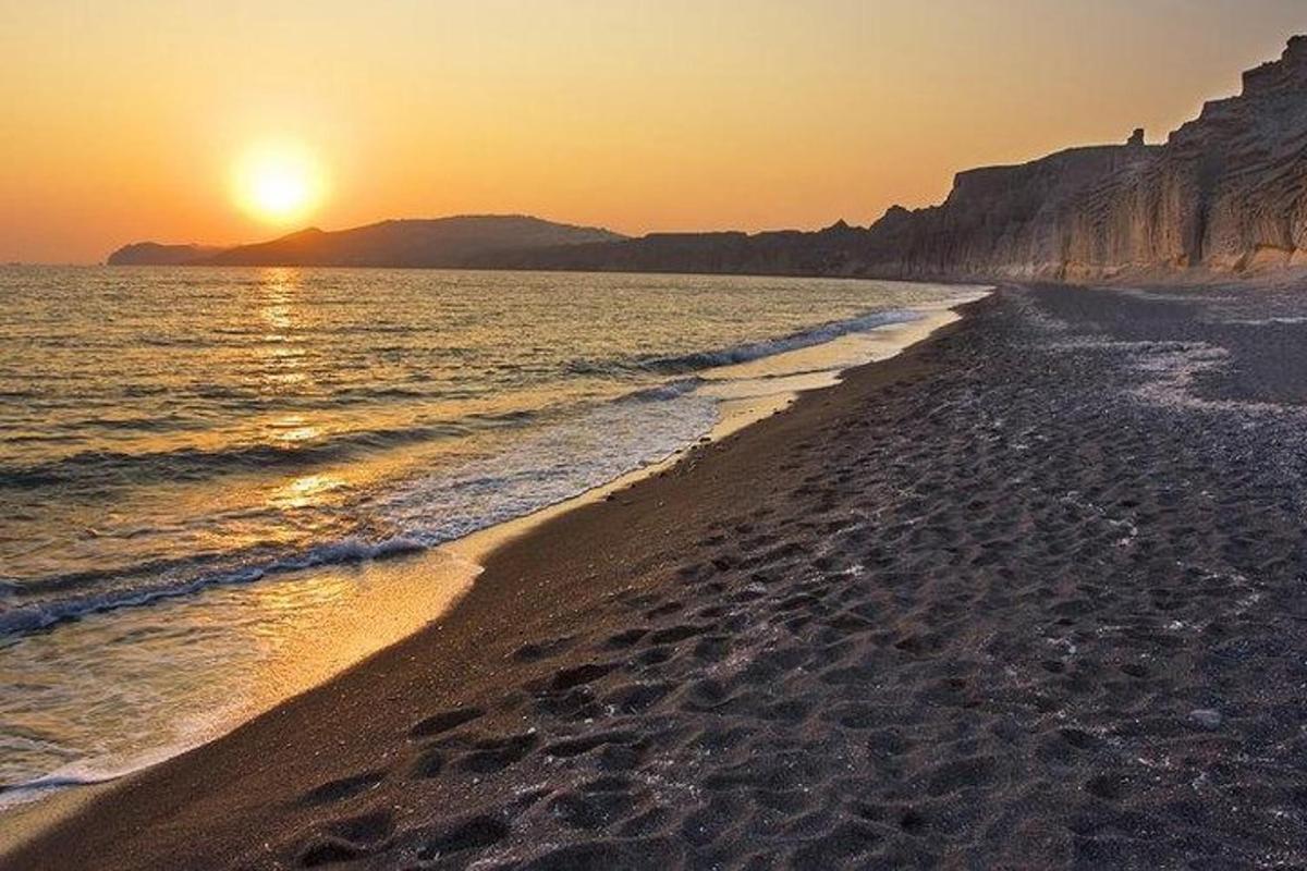 Una playa con la puesta de sol sobre el océano