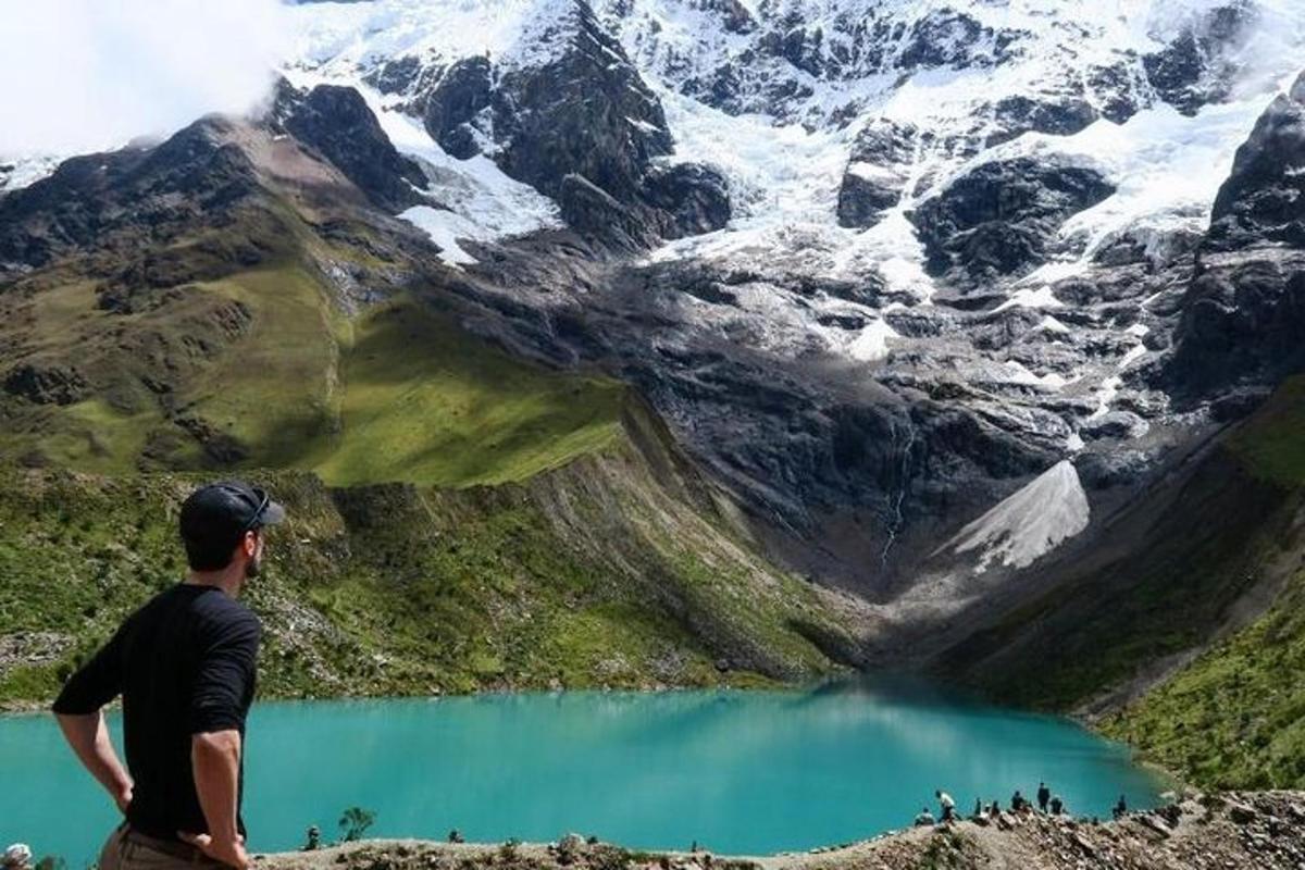 un uomo in piedi sulla cima di una montagna che guarda un lago